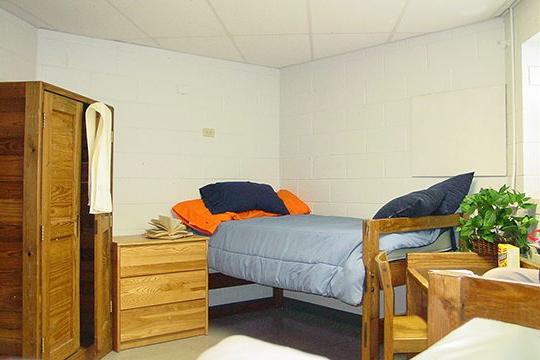 Keystone College dorm room with bed and wooden hutch and armoire